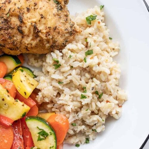 Seasoned rice on a plate with vegetables and chicken