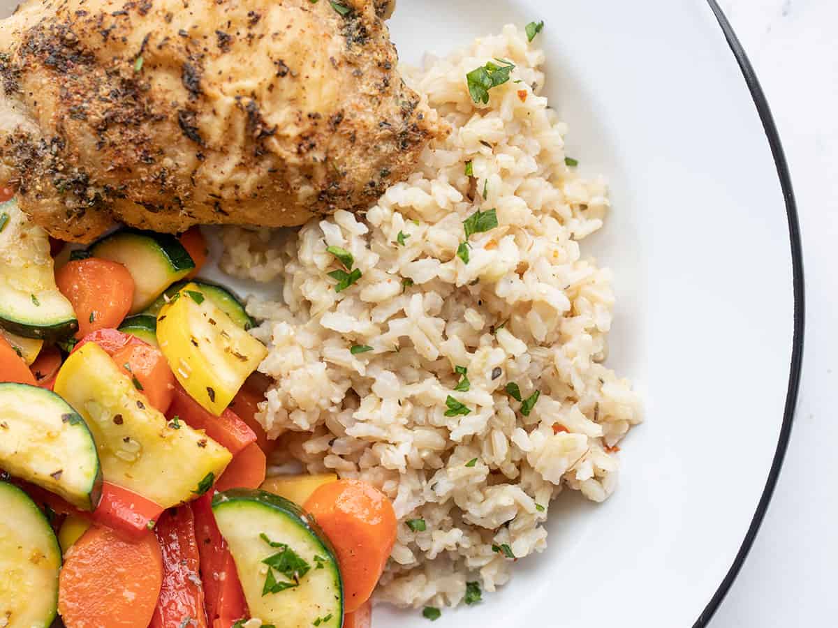 Seasoned rice on a plate with vegetables and chicken