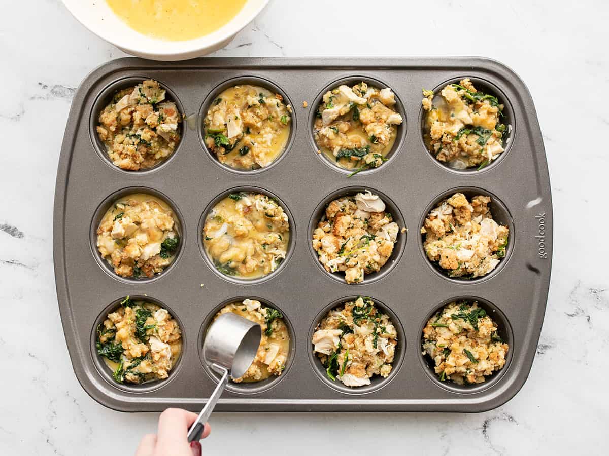 Egg mixture being scooped into the muffin tin