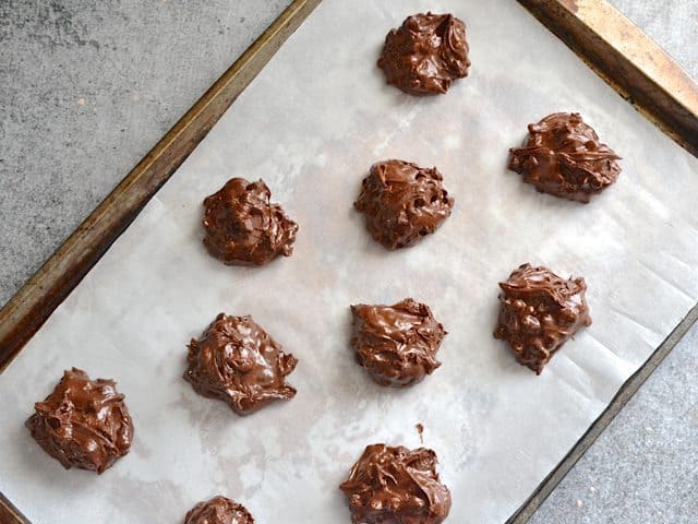 Cookie sheet lined with parchment paper with unbaked cookie dollops placed on top 