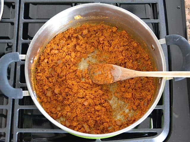 Cornmeal added to pot with other ingredients and stirred in with wooden spoon 