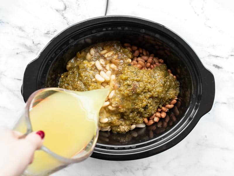 Chicken broth being poured into the slow cooker