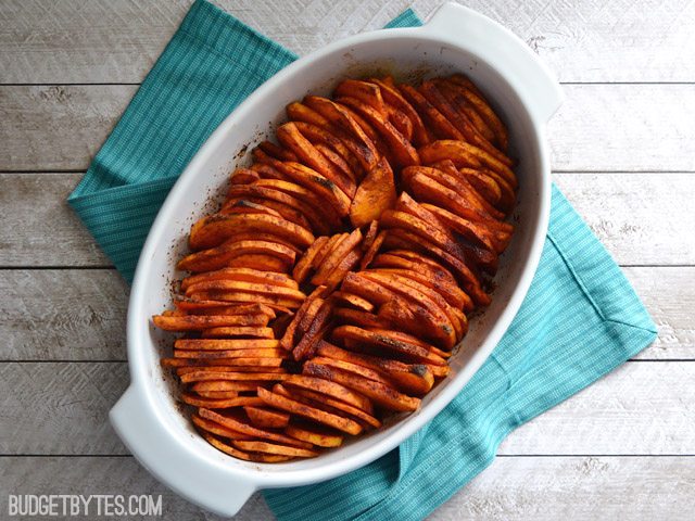 Top view of baked Smoky Roasted Sweet Potatoes in casserole dish sitting on a blue napkin 