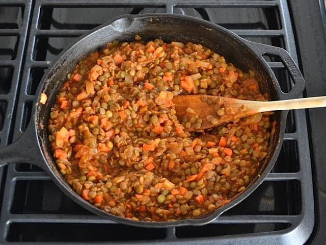 Tomato Sauce and cooked lentils added to veggie mixture in skillet and stirred with wooden spoon 