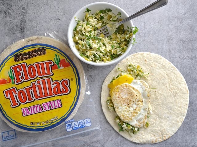 Building quesadilla. Tortilla with filling and a fried egg placed on half 