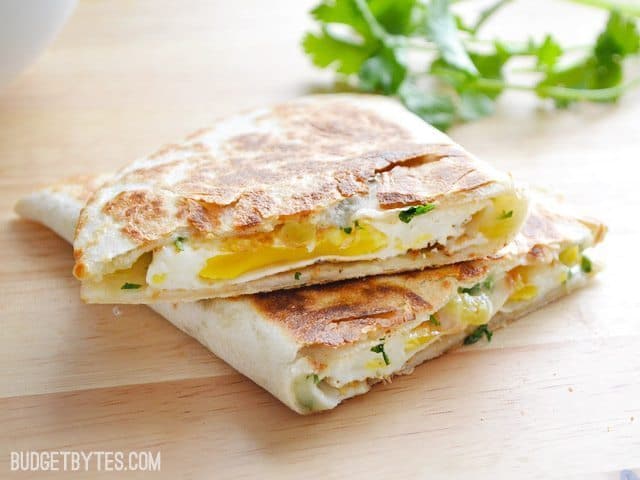 Stacked green chile breakfast quesadillas on a wooden surface.