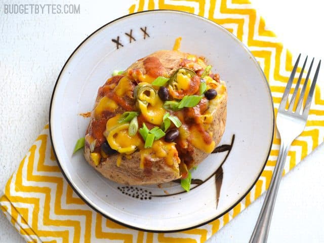 Top view of a Nacho Tater on a plate sitting on a yellow chevron napkin with a fork on the side 