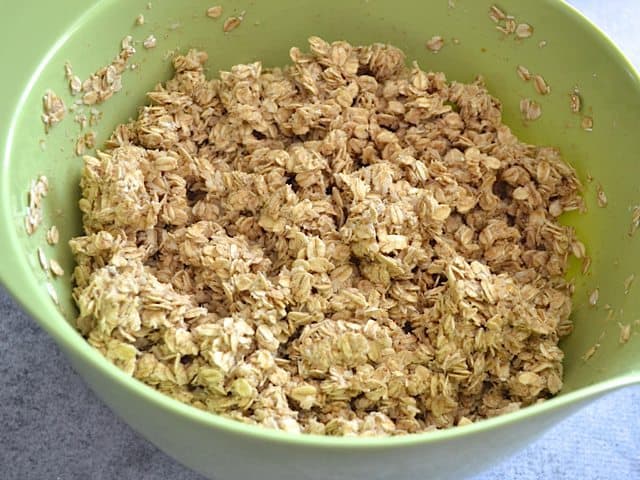 Banana sauce poured over granola mixture in mixing bowl 