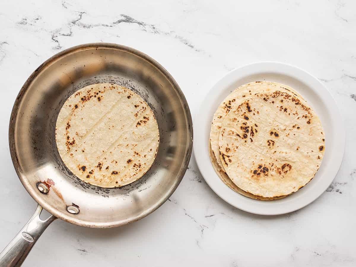 corn tortillas being toasted in a skillet