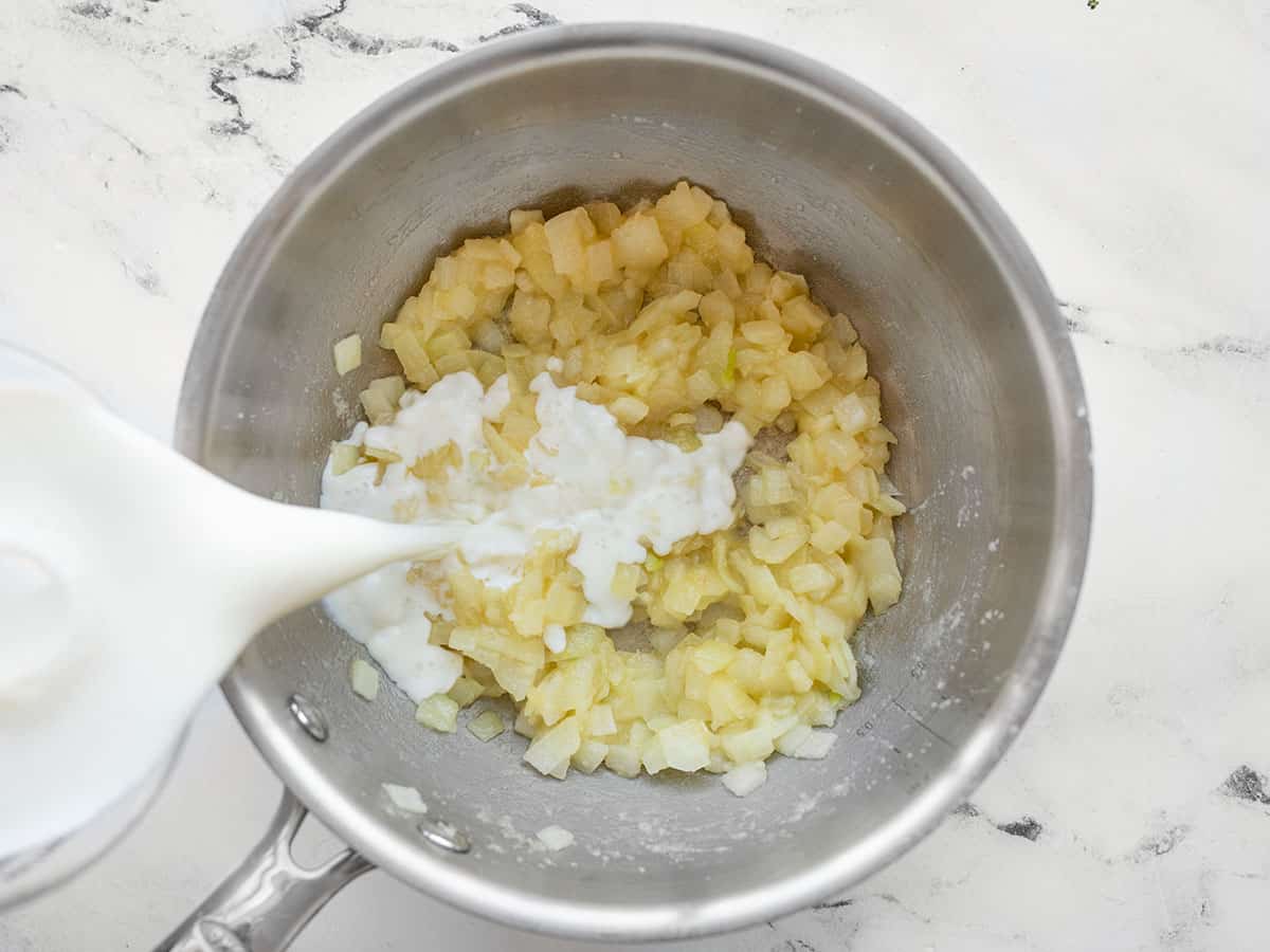 Milk being poured into the onion and flour mixture.