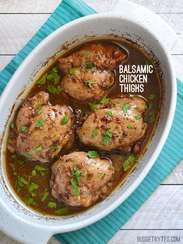 Top view of a dish of Balsamic Chicken Thighs sitting on a blue place mat 