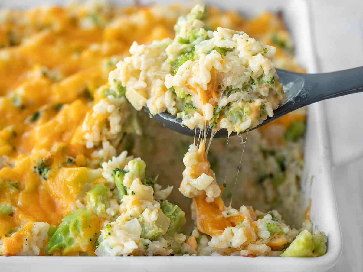 Side view of broccoli cheese casserole being lifted out of the dish with a spoon