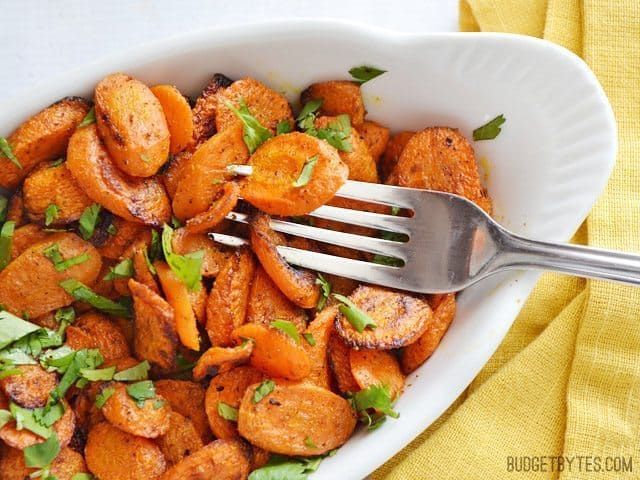 A plate of curry roasted carrots with a fork.