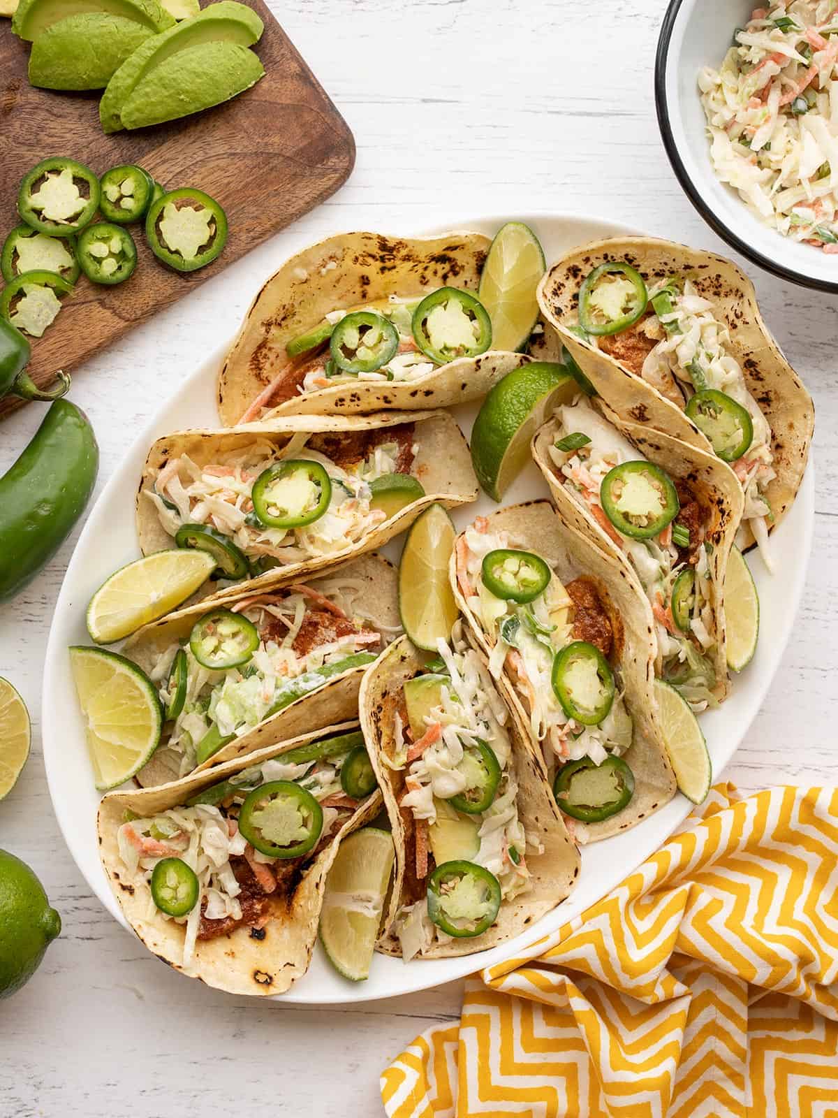 Overhead view of fish tacos on a platter, toppings on the sides