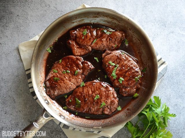 top view of a skillet of Blackberry Sage Pork Chops sitting on a gray and white napkin 