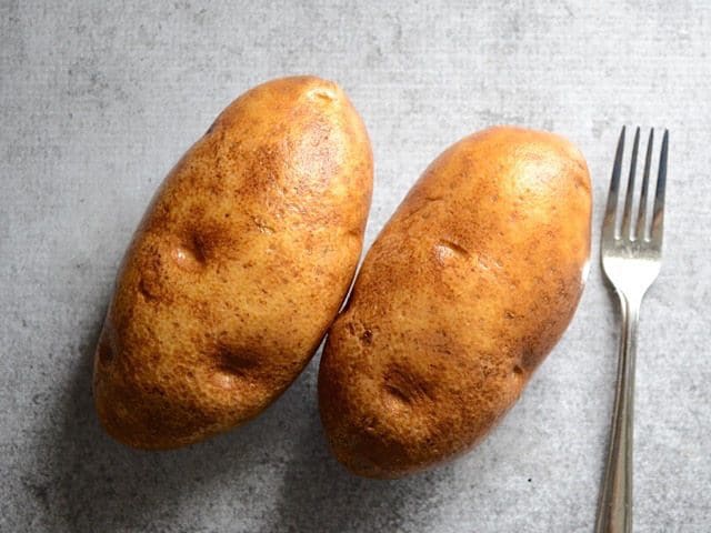 Two russet potatoes with a fork 