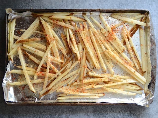 Seasoned fries placed on baking sheet lined with tin foil 