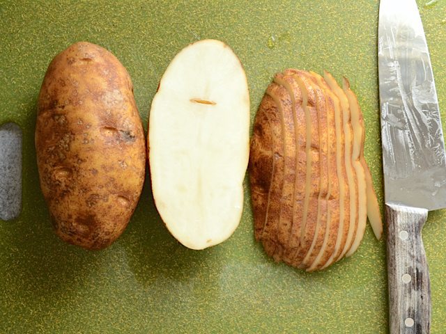 Slicing two russet potatoes with knife 