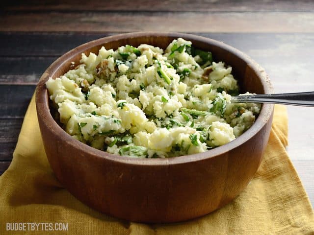 Side view of a bowl of Spinach and Feta Mashed Potatoes sitting on a yellow napkin 