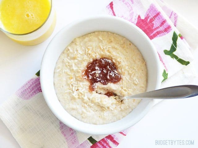 A bowl of toasted coconut oat bran with fruit and a glass of orange juice.