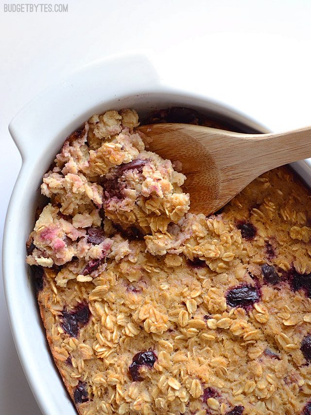 Close up of Apple Cherry Baked Oatmeal being scooped out of dish with wooden spoon 