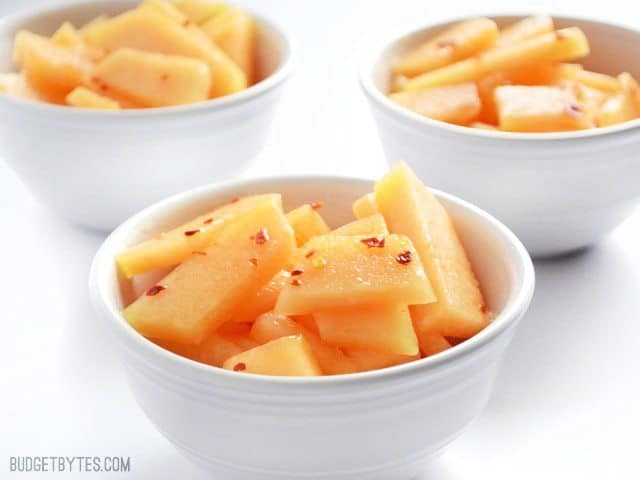 Bowls of chili lime cantaloupe garnished with herbs.