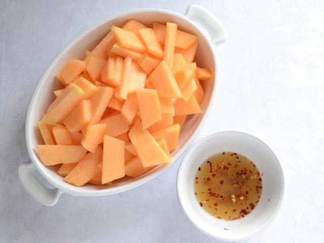 Cantaloupe in caserole dish with a small bowl of dressing on the side 