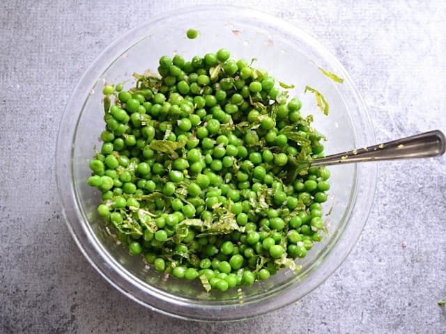 Salad ingredients mixed together in bowl with fork 