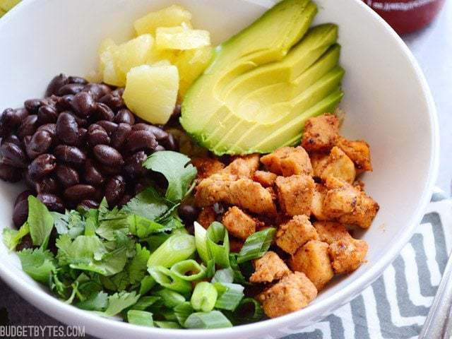 A close-up of a spicy chicken bowl with vibrant toppings.