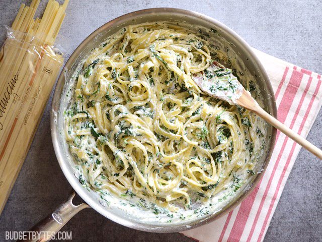 Overhead view of a skillet full of spinach ricotta pasta on a red and white striped napkin