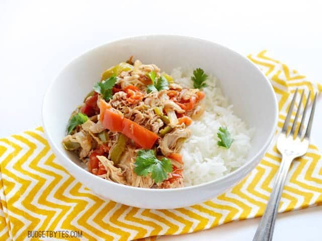 Bowl of Chicken Ropa Vieja sitting on a yellow chevron napkin with a fork on the side 