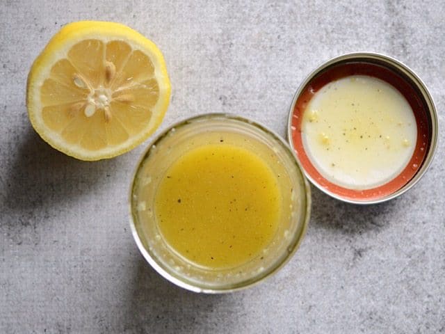 Finished Lemon Ginger Dressing in a jar next to a half lemon