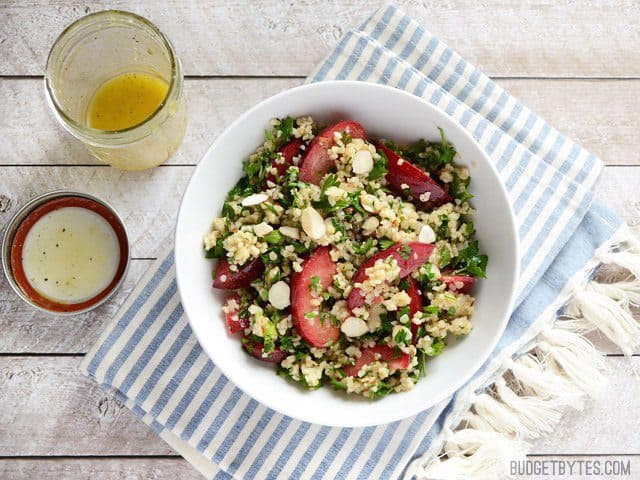 Finished Plum Salad in a bowl with a jar of dressing on the side