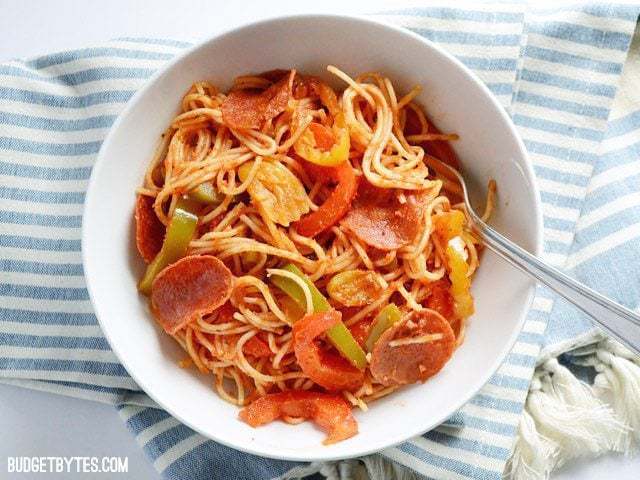 A bowl of three pepper pasta on top of a blue striped tablecloth.