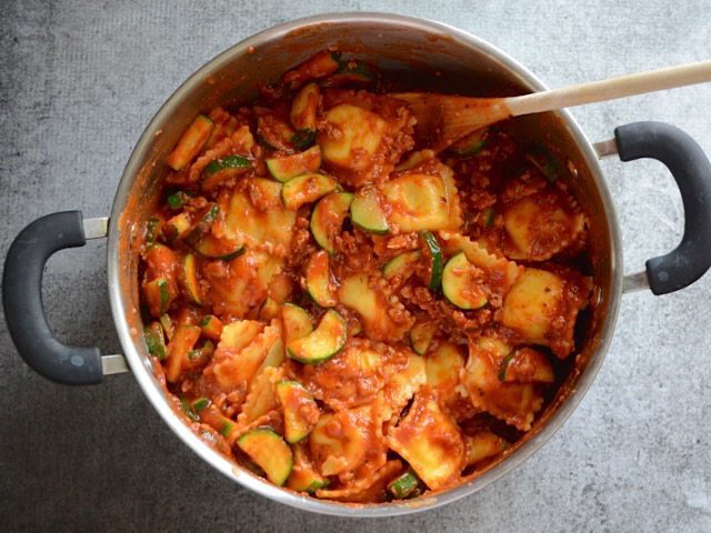 Ravioli stirred into the pot with sauce, sausage, and vegetables