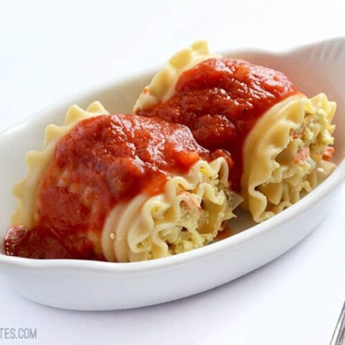 Side view of two vegetable lasagna roll ups in a serving dish