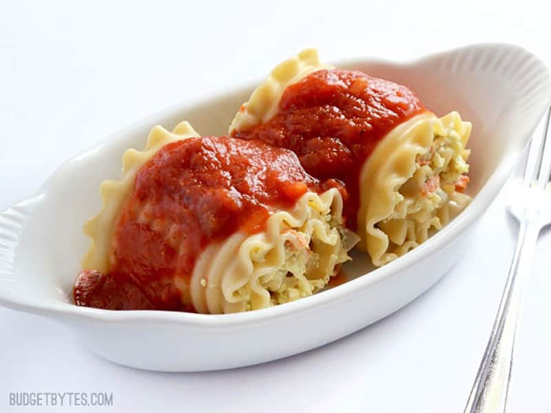 Side view of two vegetable lasagna roll ups in a serving dish