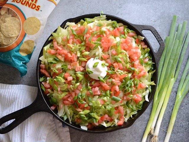 A fresh salad of lettuce, tomato, and green onion.