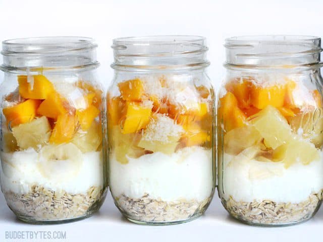 A colorful tropical yogurt parfait layered in a glass.