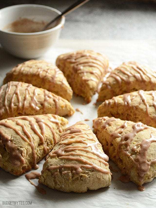 Side view of Apple Pie Scones with a bowl of glaze in the back