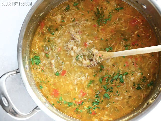 Creole White Beans with Chicken in the pot with a wooden spoon