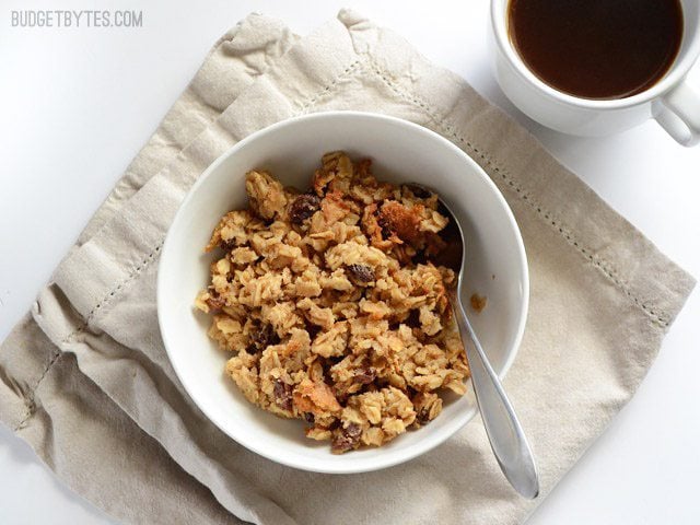 A bowl of oatmeal cookie baked oatmeal on a napkin with a mug of coffee on the side