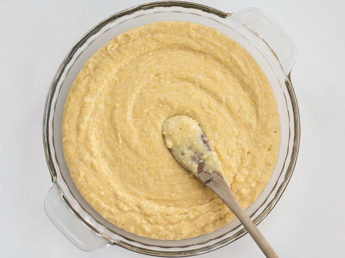 Cornbread batter in a round glass baking dish.