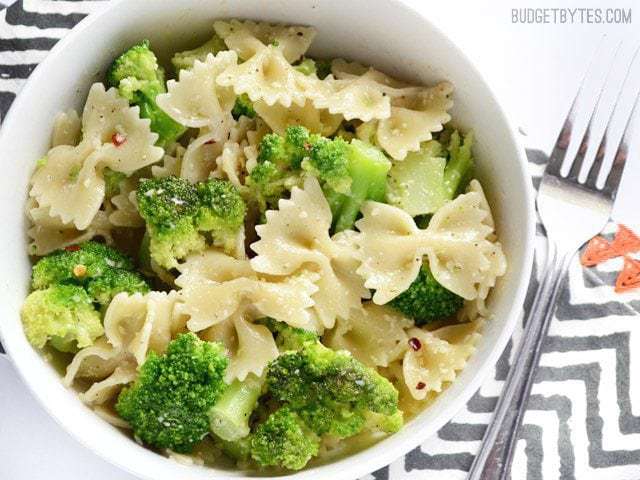 A close-up of bowtie pasta mixed with broccoli and sauce.