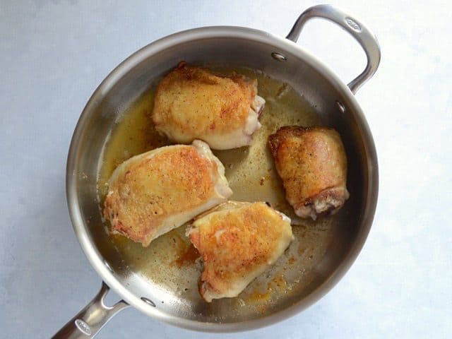 browned chicken thighs in a deep skillet