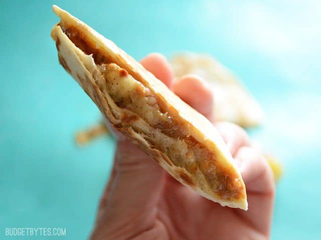 Side view of a cut Caramelized Banana and Peanut Butter Quesadillas being held close to the camera