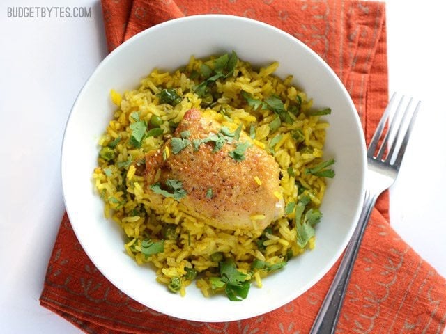 A bowl of Yellow Rice with chicken on a red napkin