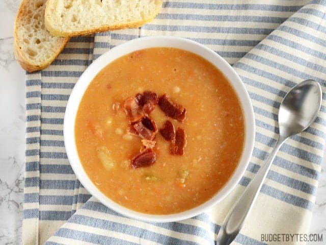 Over head view of a bowl of Bacon Bean and Potato Soup ready to serve with bread