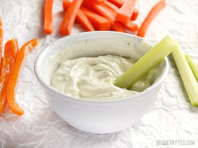 A bowl of dilly vegetable dip served with celery sticks.