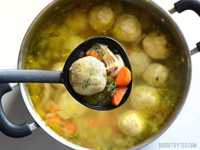 Close up of a label full of Matzo Ball Soup being held over the pot 